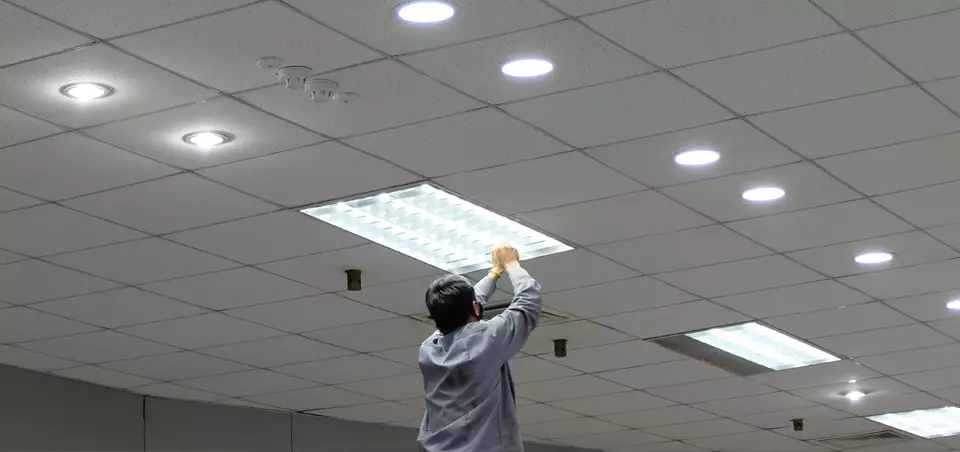 man changing a light in an office ceiling